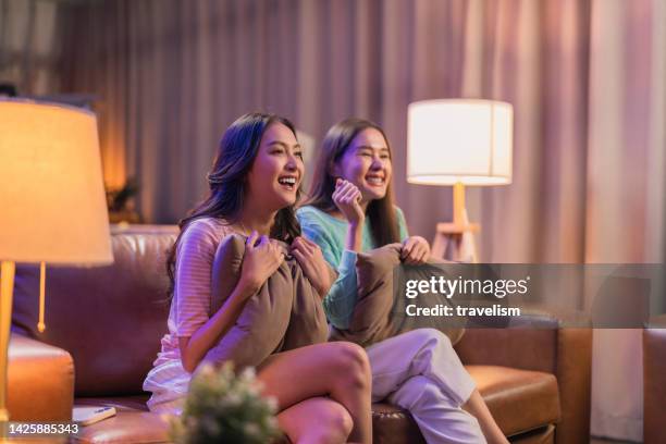 two asian adult female woman watching favourite movie actor singer on television at the home on holiday trip night time - dramafilm stockfoto's en -beelden