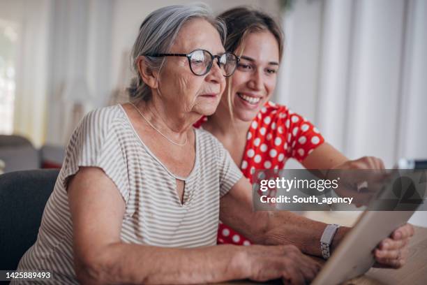 grandmother and granddaughter use tablet - volunteer home care stock pictures, royalty-free photos & images