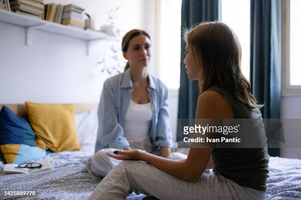 mother and daughter talking at home - parents stockfoto's en -beelden