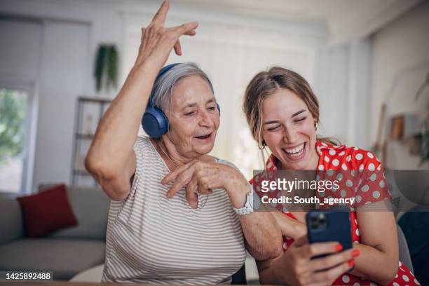 grandmother and granddaughter use smart phone and headphone - family singing stock pictures, royalty-free photos & images