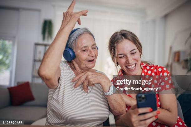 grandmother and granddaughter use smart phone and headphone - singing grandma stock pictures, royalty-free photos & images