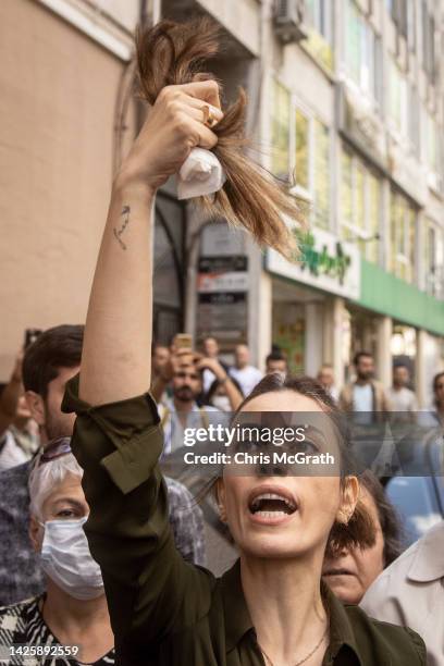 Woman holds up a handful of her hair after cutting it during a protest over the death of Iranian Mahsa Amini outside the Iranian Consulate on...