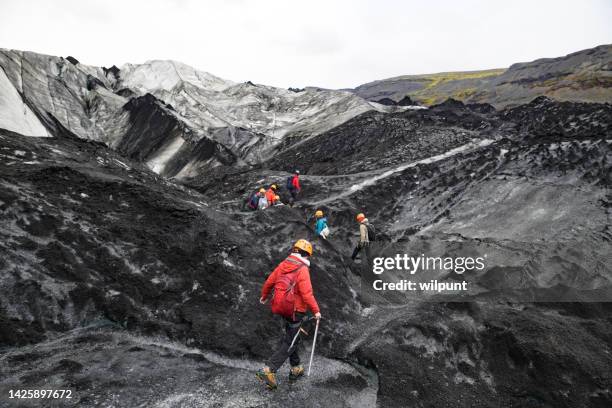 geführte gruppe von wanderern mit steigeisen, die den sólheimajökull-gletscher befahren - icepick stock-fotos und bilder