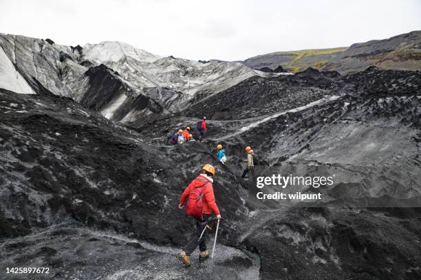 guided tour group of hikers with crampons navigating sólheimajökull glacier - icepick stock pictures, royalty-free photos & images