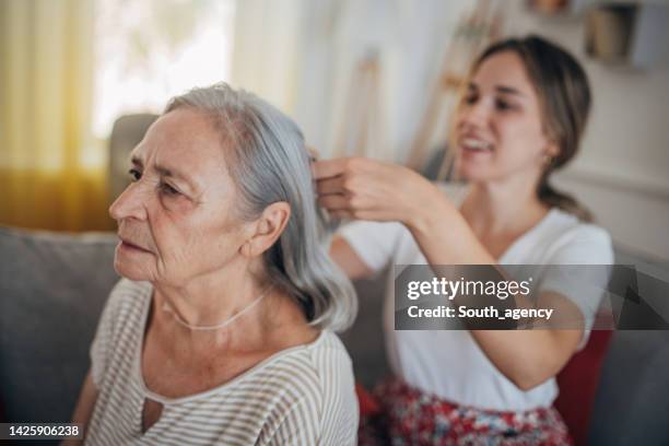 granddaughter combing grandmother's hair - brushing hair stock pictures, royalty-free photos & images