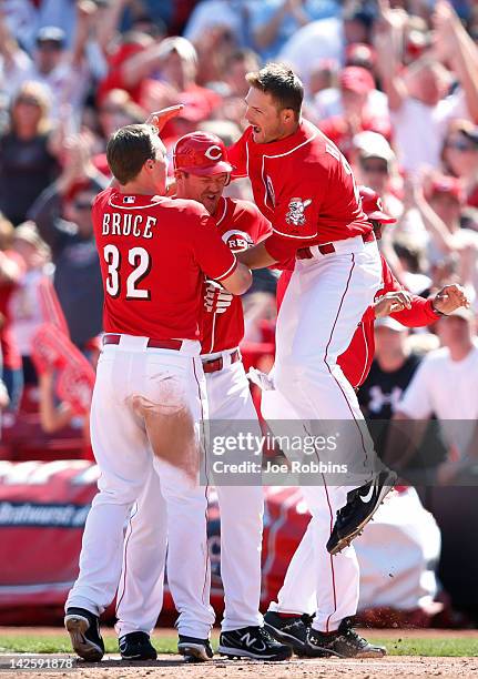 Jay Bruce and Chris Heisey of the Cincinnati Reds celebrate with teammate Scott Rolen after his game-winning hit in the bottom of the ninth inning...