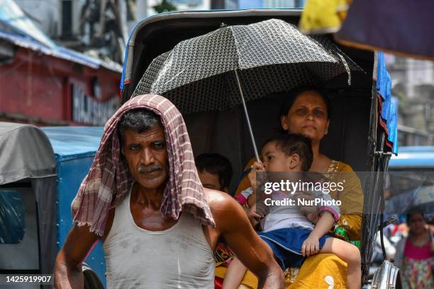 Mother is seen holding an umbrella over her child inside a hand pulled rickshaw to escape from heat wave , as seen in Kolkata , India , on 3 July...