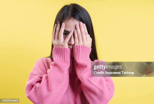 a picture of a scared woman covering her eyes over pink background - gesicht verstecken stock-fotos und bilder