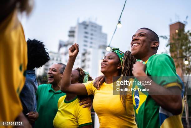 brazilian sports team fan watching a match and celebrating outdoors - world cup brazil stock pictures, royalty-free photos & images