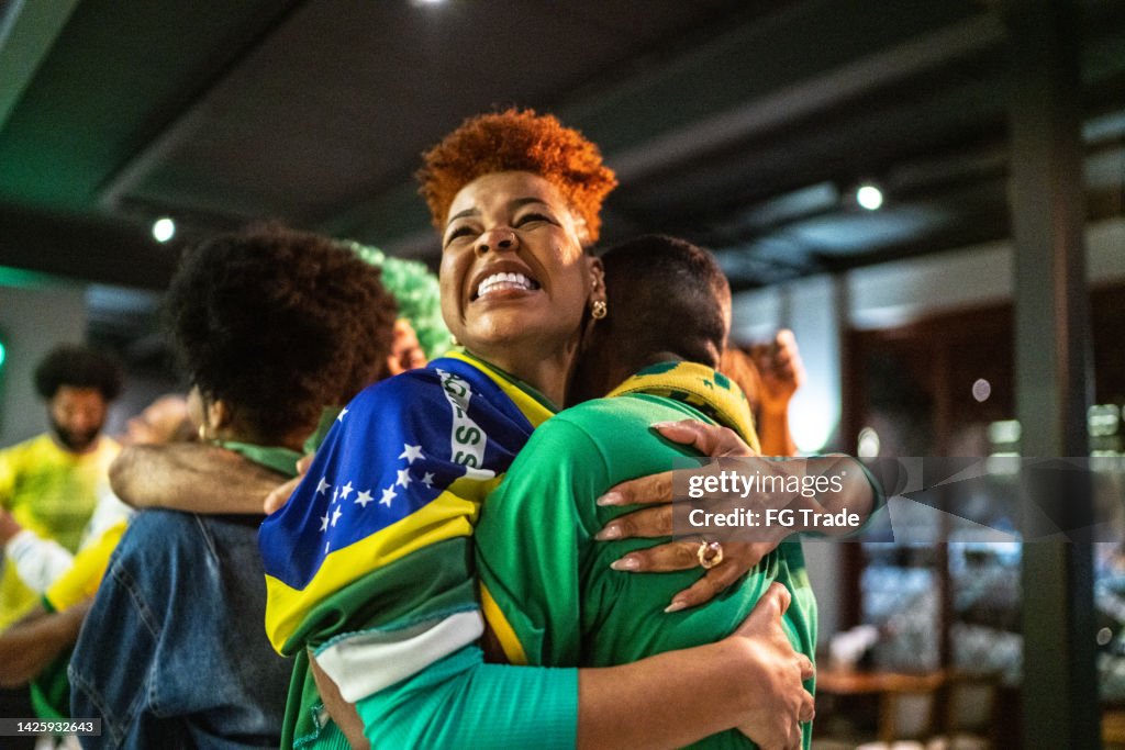 Brazilian sports fans watching match and celebrating at a bar