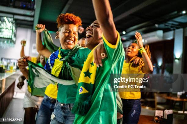 brasilianische sportfans, die sich das spiel ansehen und in einer bar feiern - female fans brazil stock-fotos und bilder