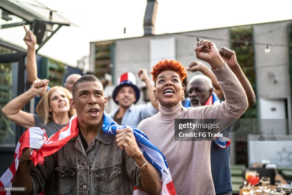 American sports team fans watching a match and celebrating outdoors