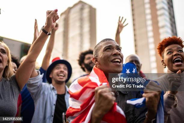 american sports team fans watching a match and celebrating outdoors - basketball match on tv stockfoto's en -beelden
