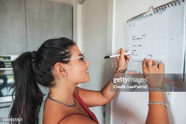 frau notiert sich den küchenkalender - foto kalender stock-fotos und bilder