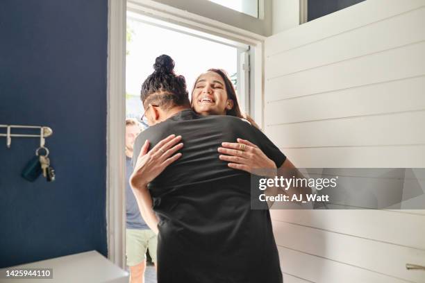 young woman greeting a friend with a hug at his front door - man opening door woman bildbanksfoton och bilder