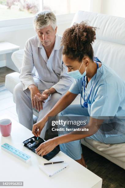 nurse visiting diabetic senior man at home - diabetes technology stock pictures, royalty-free photos & images