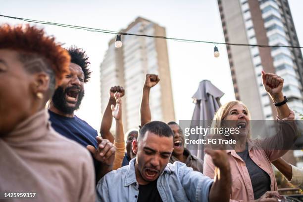sports fans watching a match and celebrating at a bar rooftop - basketball match on tv stockfoto's en -beelden