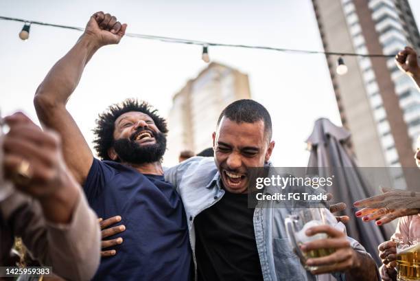 les amateurs de sport regardent un match et font la fête sur le toit d’un bar - black and white photo out door sport photos et images de collection