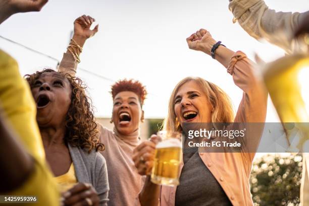 sports fans watching a match and celebrating at a bar rooftop - crowd of brazilian fans stockfoto's en -beelden