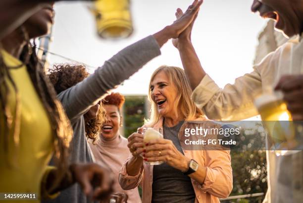 sports fans watching a match and celebrating at a bar rooftop - bar atmosphere stock pictures, royalty-free photos & images