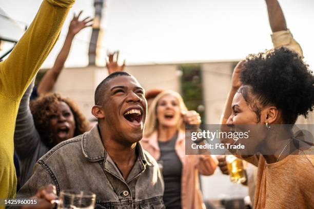 sports fans watching a match and celebrating at a bar rooftop - crowd cheering bar stock pictures, royalty-free photos & images