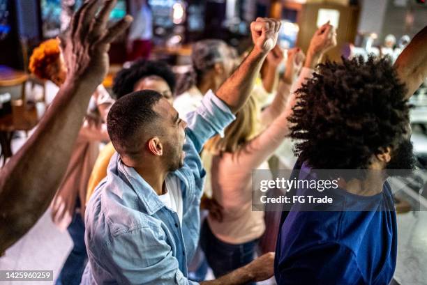 sports fans watching a match and celebrating at a bar - social tv awards stockfoto's en -beelden