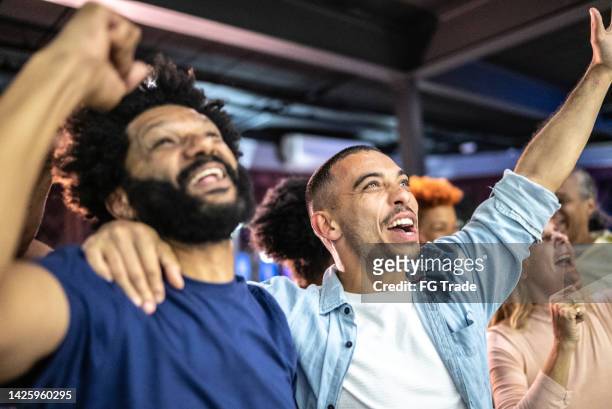 sports fans watching a match and celebrating at a bar - voetbalcompetitie sportevenement stockfoto's en -beelden