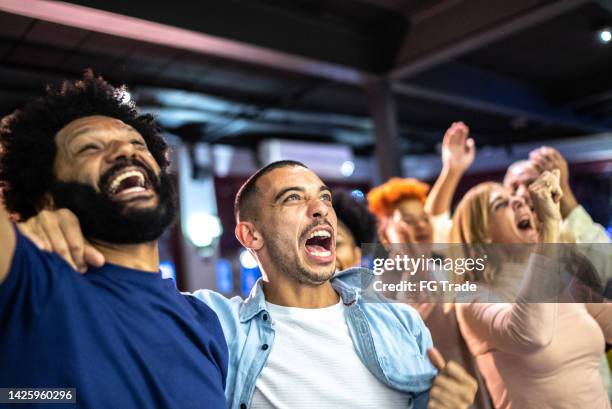 sports fans watching a match and celebrating at a bar - social tv awards stockfoto's en -beelden