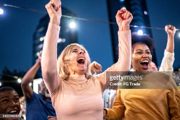 sports fans watching a match and celebrating at a bar rooftop - concert fans stock pictures, royalty-free photos & images