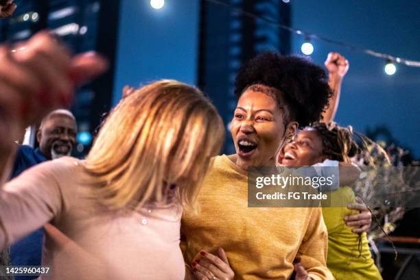 sports fans watching a match and celebrating at a bar rooftop - basketball match on tv stockfoto's en -beelden