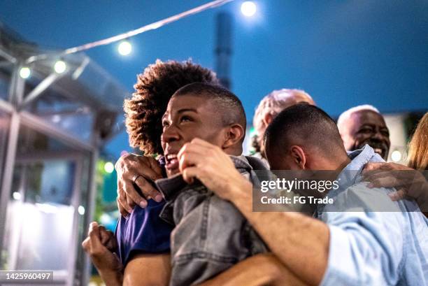 sports fans watching a match and celebrating at a bar rooftop - social tv awards stockfoto's en -beelden