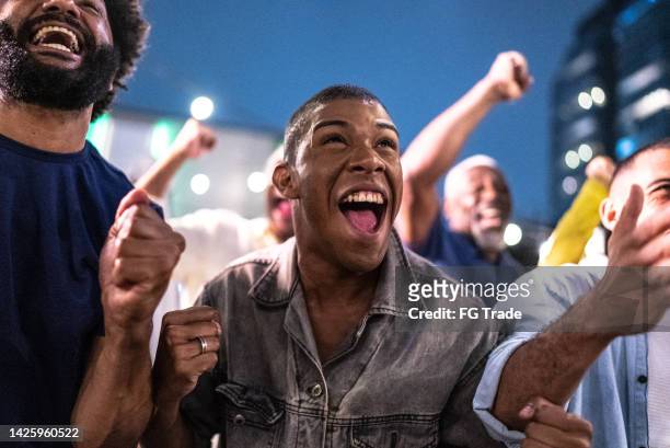 sports fans watching a match and celebrating at a bar rooftop - sport crowd stock pictures, royalty-free photos & images