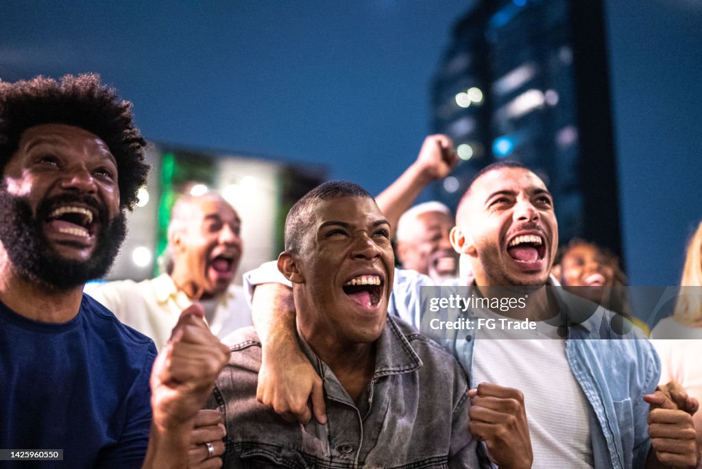 Sportfans, die sich ein Spiel ansehen und auf dem Dach einer Bar feiern