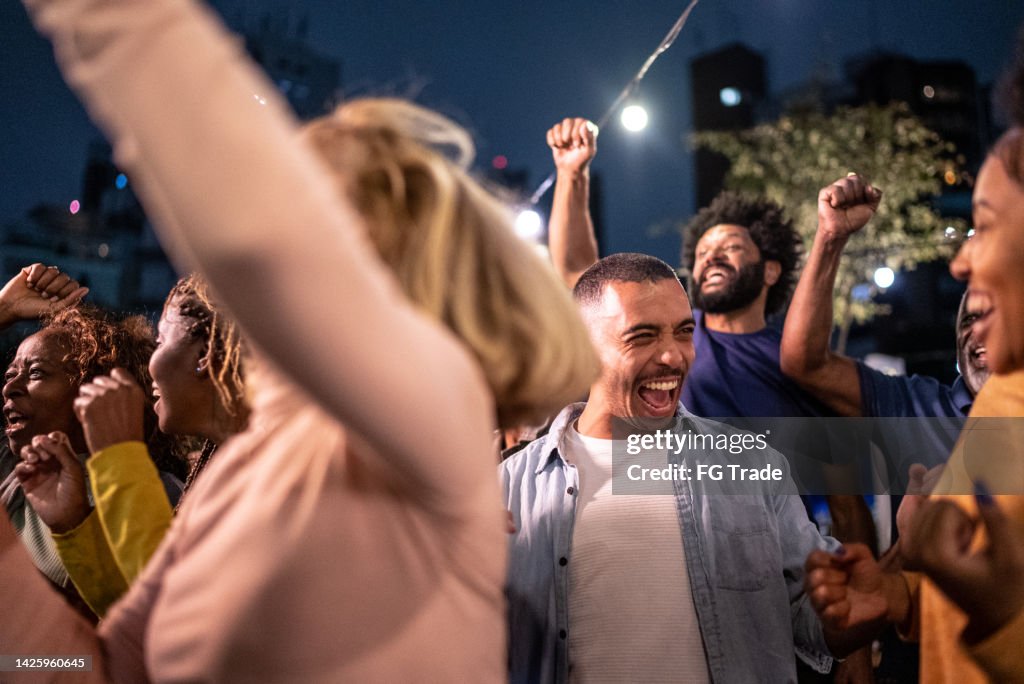 Sports fans watching a match and celebrating at a bar rooftop