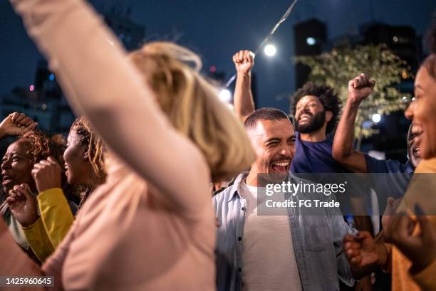 sports fans watching a match and celebrating at a bar rooftop - music fans bildbanksfoton och bilder