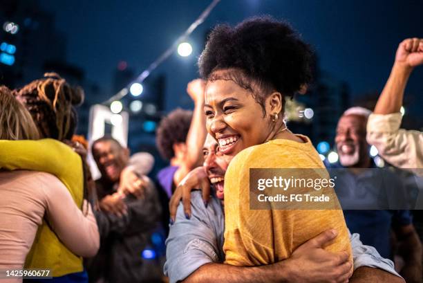 fãs de esportes assistindo a uma partida e celebrando em um telhado de bar - winning - fotografias e filmes do acervo