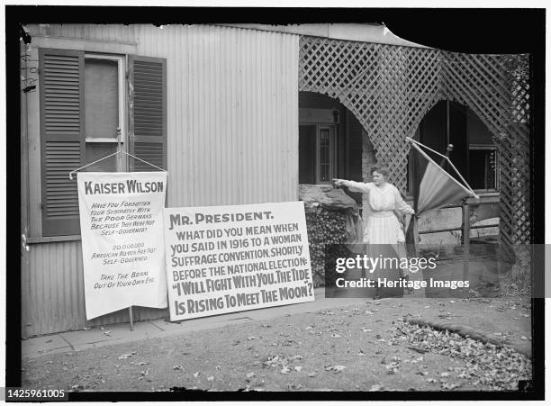 Woman suffrage banners, between 1916 and 1918. First World War: woman pointing at banners reading: 'Kaiser [Woodrow] Wilson, have you forgotten your...