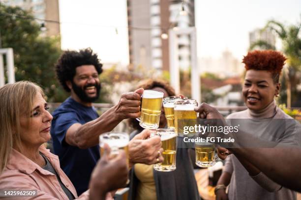 friends doing a celebratory toast with beer during happy hour - beer cheers stock pictures, royalty-free photos & images