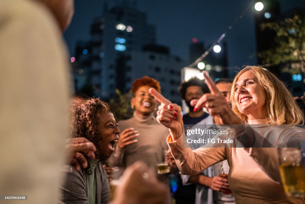 Happy friends dancing during party at night
