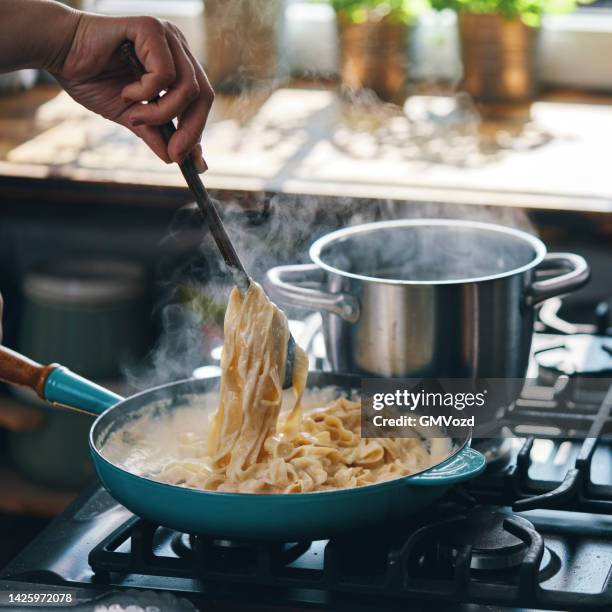 preparing fettuccine pasta alfredo with parmesan - alfredo sauce stock pictures, royalty-free photos & images