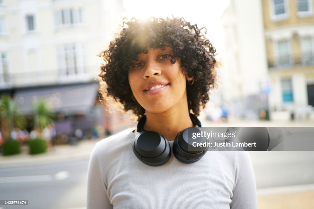 Woman posing with wireless headphones with the bright sun behind her