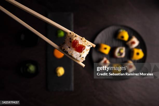 hand holding sushi with chopsticks - bento imagens e fotografias de stock