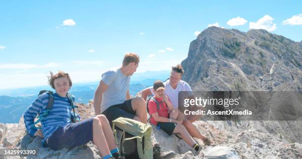 family of hikers enjoy a break on a mountain summit - teen boy shorts stock pictures, royalty-free photos & images