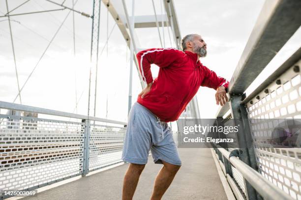 senior sporty man having back pain - trail running back stock pictures, royalty-free photos & images