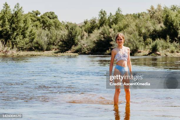 une adolescente patauge dans une rivière peu profonde - fille maillot photos et images de collection