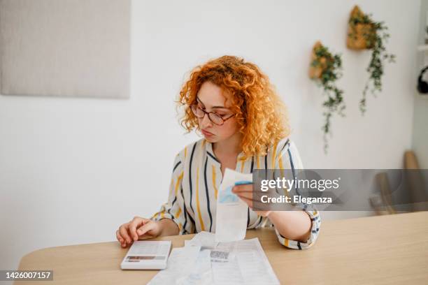 shot of a young woman looking stressed out while calculating home  finances at home office - expense receipts stock pictures, royalty-free photos & images