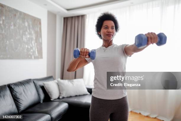 determined woman losing weight at home and exercising with dumbbells. sporty pretty woman exercising at home with dumbbells. fitness, workout, healthy living and diet concept. - hand weight stock pictures, royalty-free photos & images