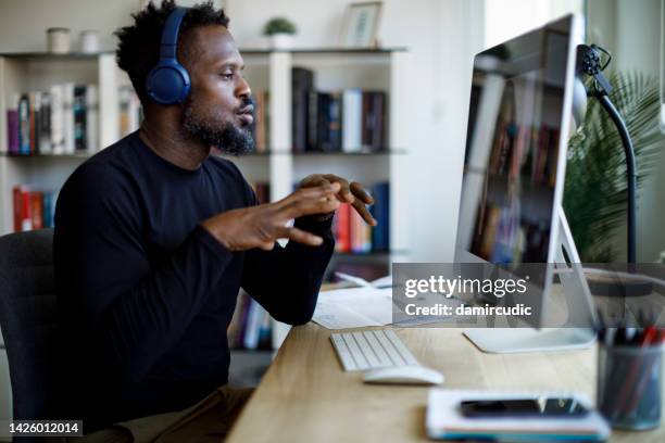 hombre con auriculares que tiene videollamada en la oficina en casa - realidad virtual fotografías e imágenes de stock