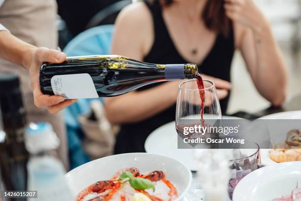 waiter pouring wine for customers in luxury outdoor restaurant - wijn proeven stockfoto's en -beelden