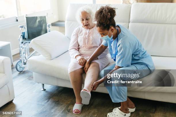 senior woman getting physical therapy treatment at home - blodkärl bildbanksfoton och bilder